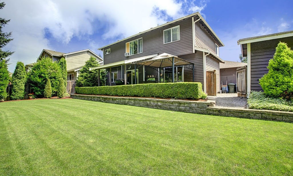 Manicured backyard lawn with a stone retaining wall in Fitchburg, MA